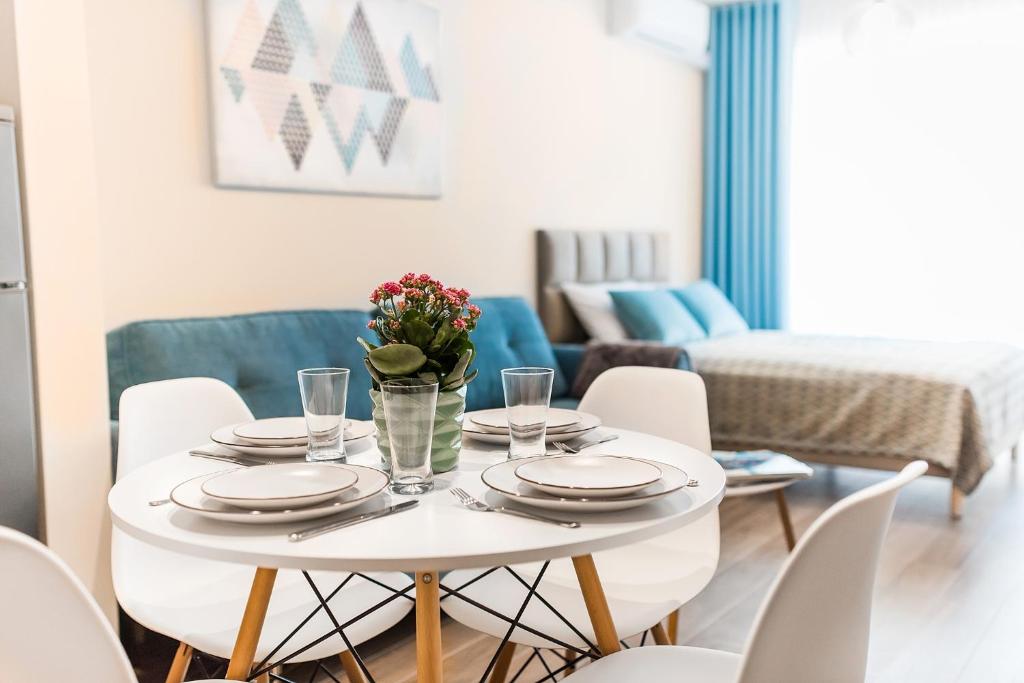尤斯托尼莫斯基Apartamenty Silence&Sea Dwie Sosny的白色的餐桌,上面有盘子和鲜花