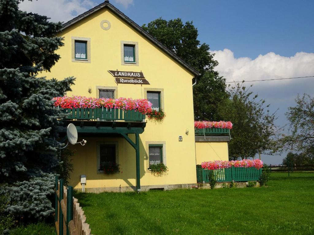 RathmannsdorfLandhaus Rundblick im Elbsandsteingebirge bei Bad Schandau的黄色的房子,里面装有花盒