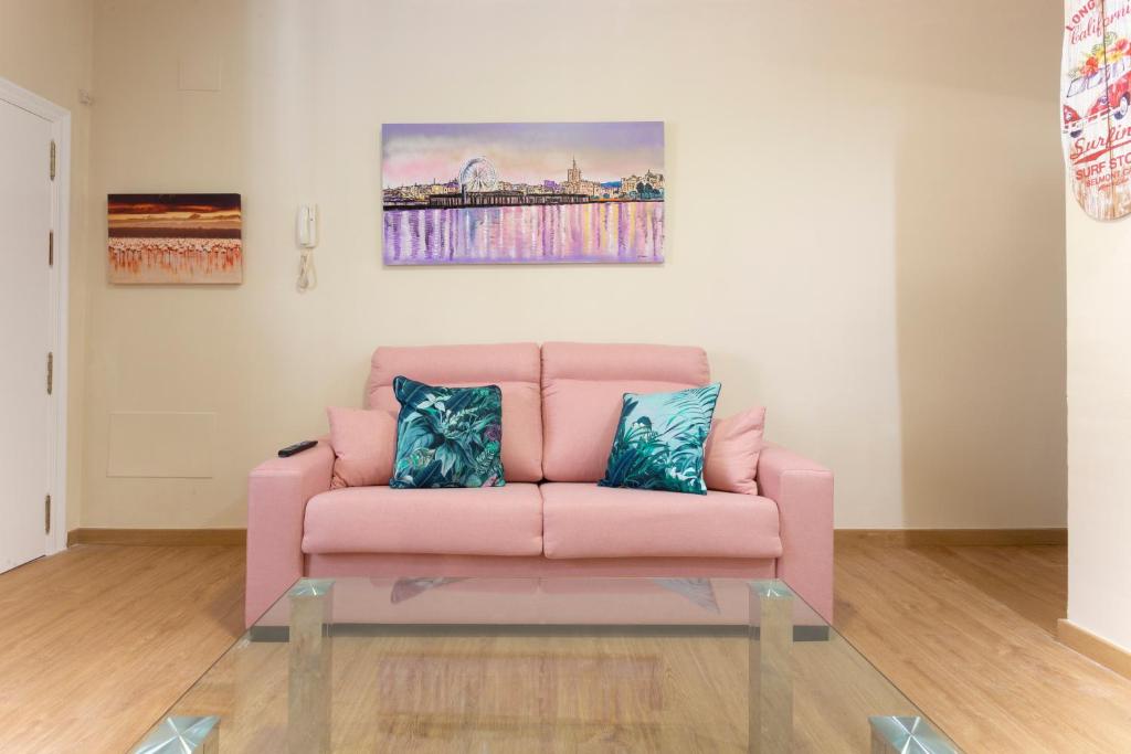 马拉加Flamingo Apartment的客厅配有粉红色的沙发,设有玻璃桌