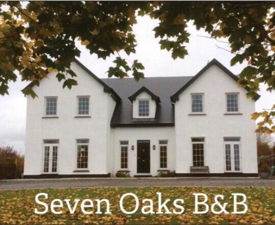 巴利霍尼斯Seven Oaks B&B的白色的房子,上面写着发光的橡树bdb
