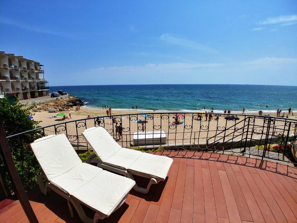 敖德萨Котеджі на приватному пляжу - Совіньон 2024的两把白色椅子坐在俯瞰着海滩的阳台上
