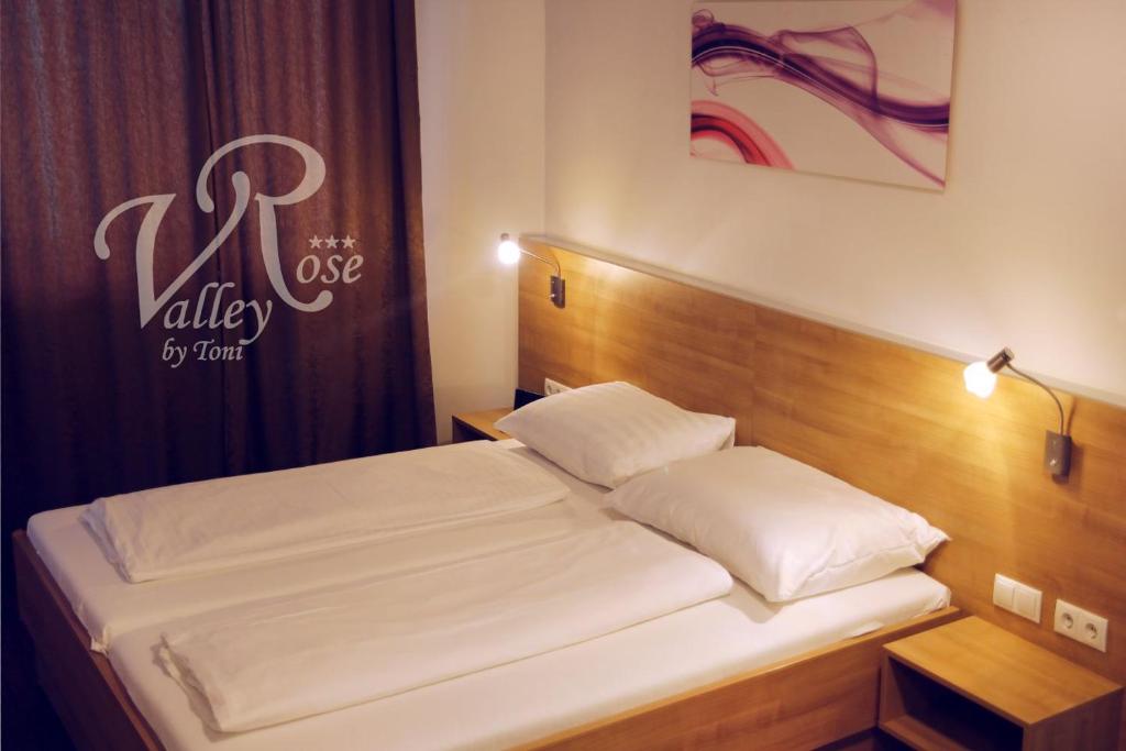 维也纳玫瑰谷餐厅酒店的一间卧室配有一张带木制床头板的床