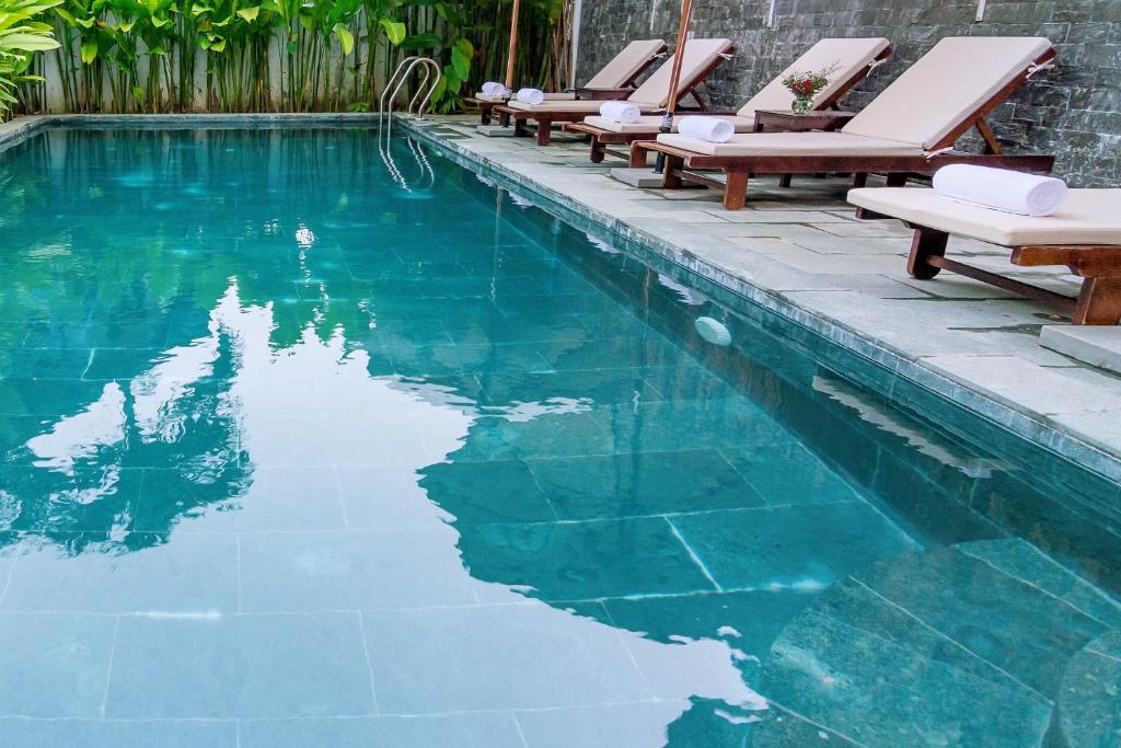 会安安邦海滩别墅的一个带椅子的游泳池,海水蓝色