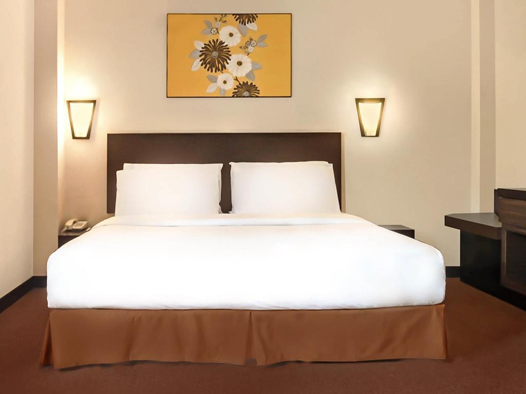 吉隆坡豪景酒店的一间卧室配有一张带两盏灯的大型白色床。