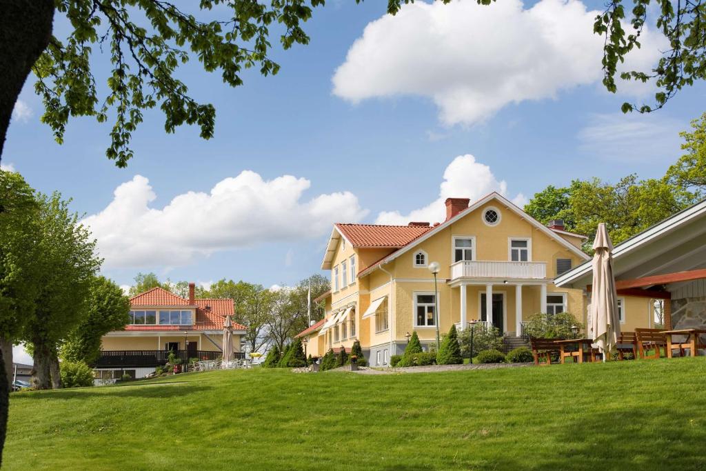 韦克舍Sure Hotel by Best Western Ojaby Herrgard的一座带绿色草坪的大型黄色房屋