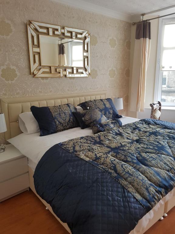 邓巴顿Loch Lomond Apartments的一间卧室配有一张大床和镜子