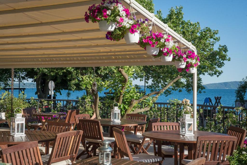 特雷维尼亚诺罗马诺Malì Trevignano Piccolo Hotel的庭院设有木桌、椅子和鲜花