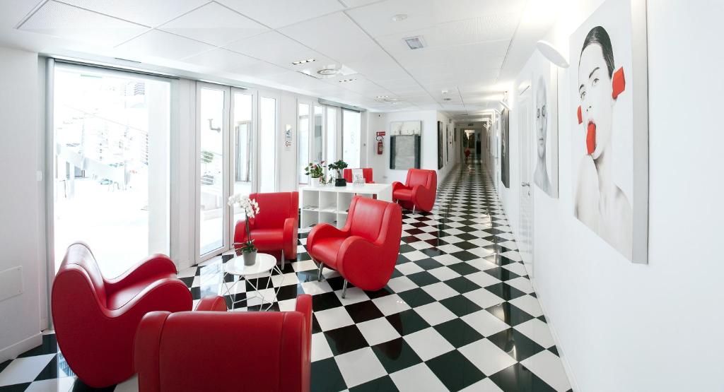 米兰Hotel Studio Inn Centrale & Milano Urban Padel的一间设有红色椅子和 ⁇ 格地板的等候室