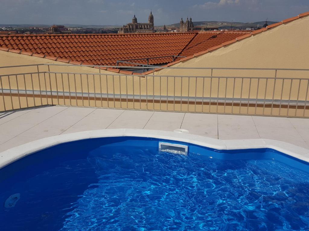 萨拉曼卡阿拉梅达宫酒店的一座大型蓝色游泳池,位于一座建筑的顶部