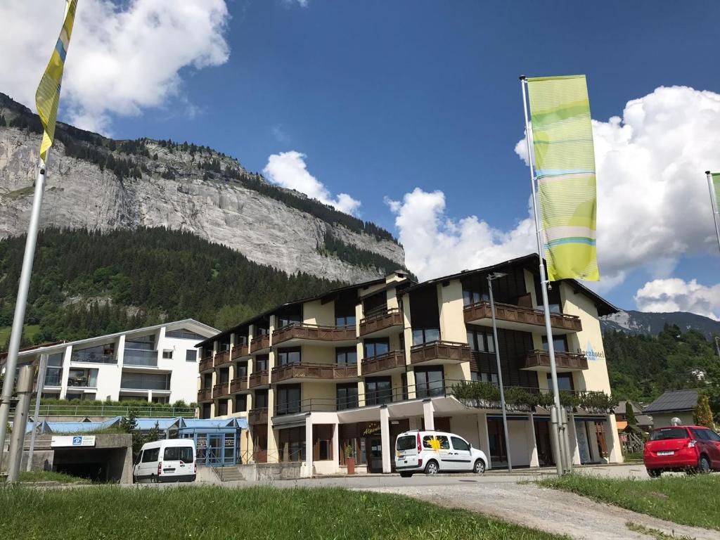 弗利姆斯T3 Alpenhotel Flims的山前有车辆停放的建筑物