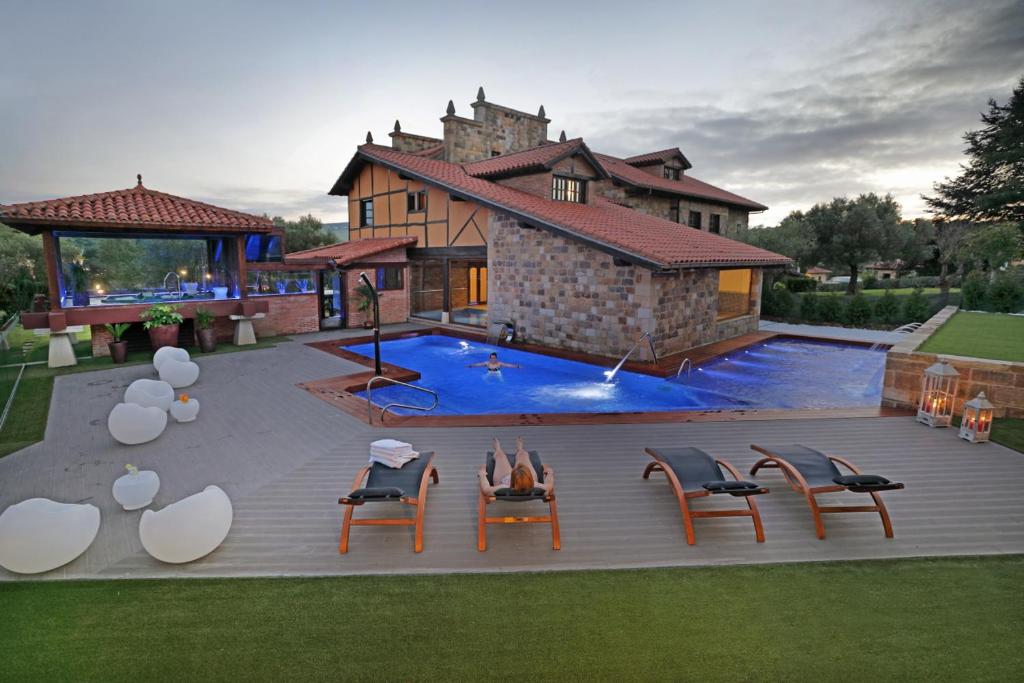 桑提亚纳德玛Posada Spa San Marcos的一座房子,一座带椅子的游泳池和一座建筑