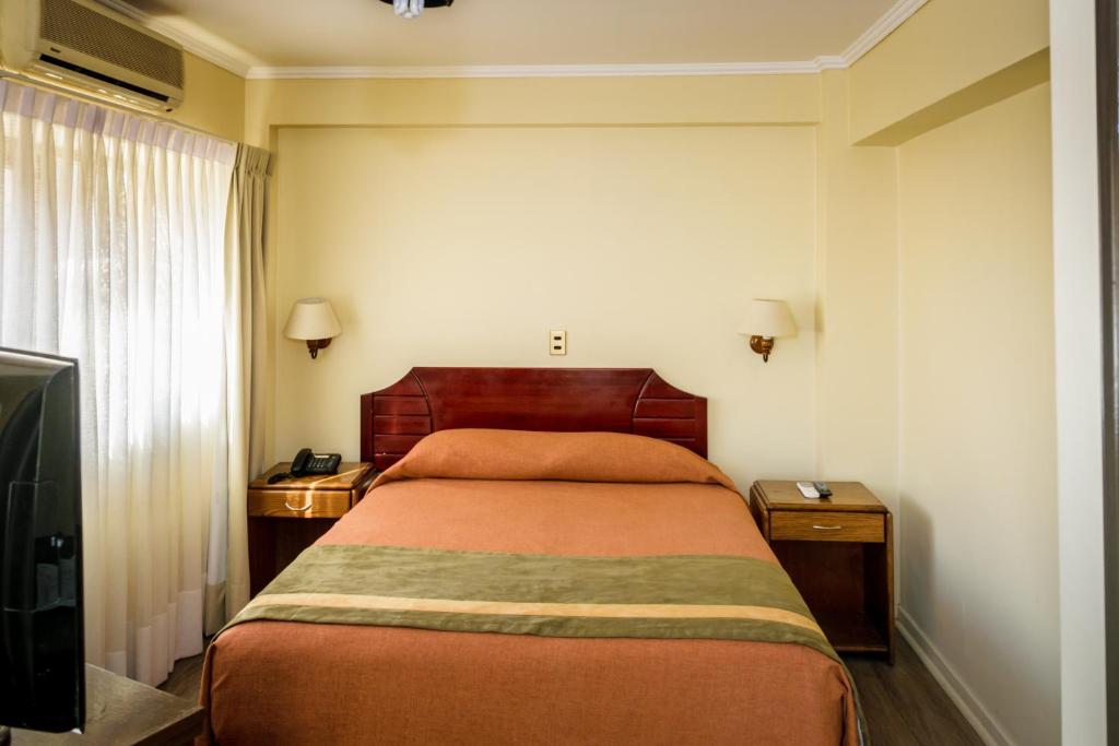 安托法加斯塔Hotel Diego de Almagro Antofagasta Express的一间卧室配有床、两个床头柜和电视