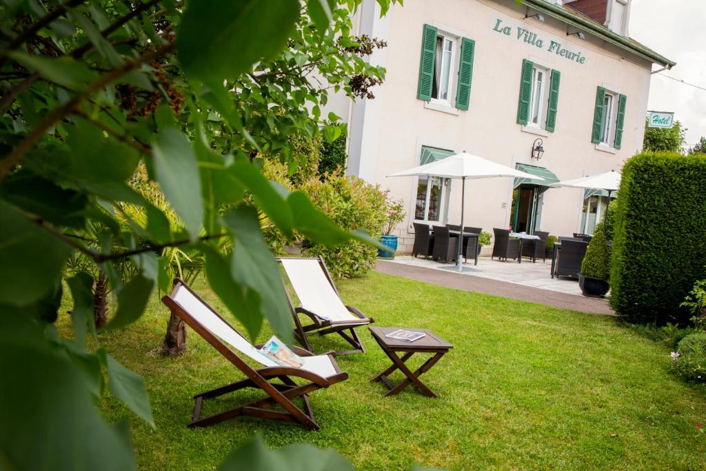 博讷花园城市酒店的建筑物前面的草上两把椅子和一张桌子