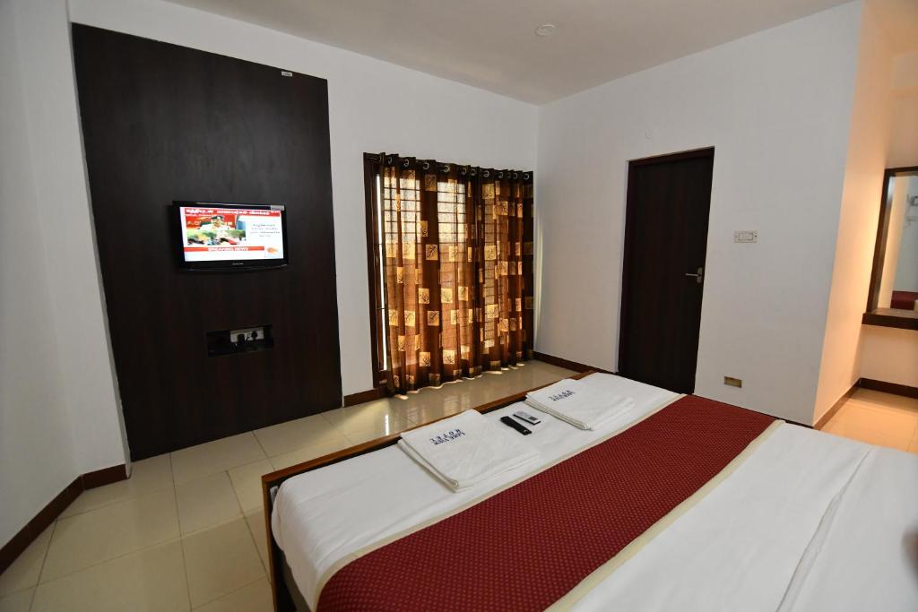 马杜赖Lake View Hotel的卧室配有一张大床,墙上配有电视