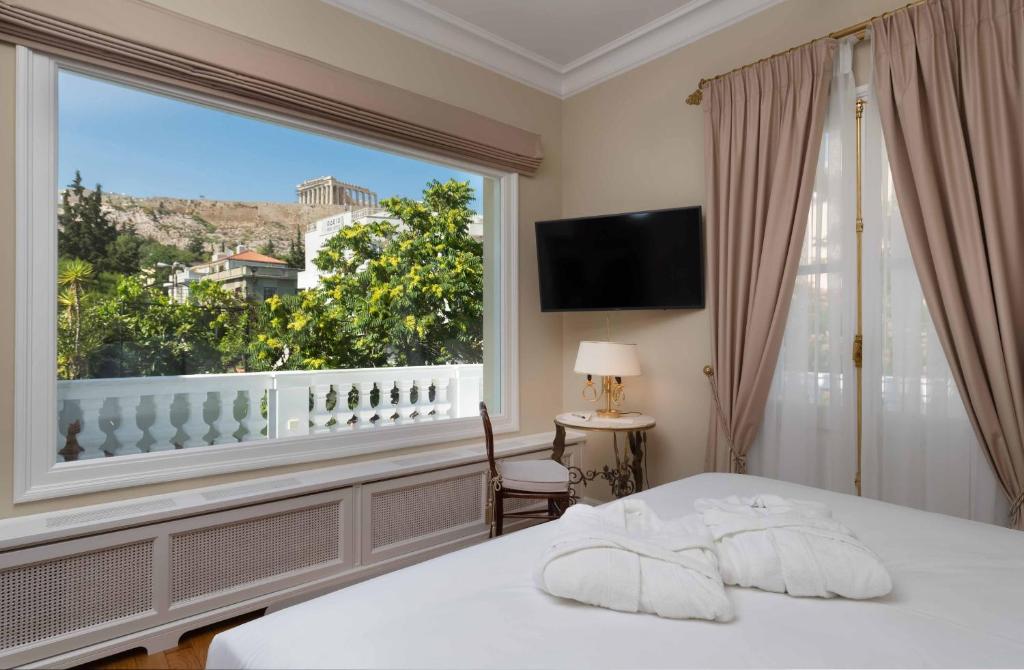 雅典贵族套房公寓式酒店的一间卧室设有一张床和一个大窗户