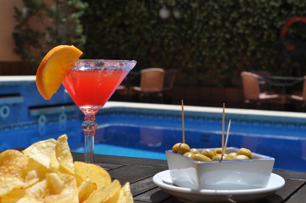 滨海托萨Hotel Mar de Tossa的池畔桌子上的饮料和薯条