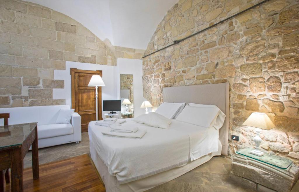 莱切Chiesa Greca - SIT Rooms & Apartments的一间卧室设有一张大床和石墙