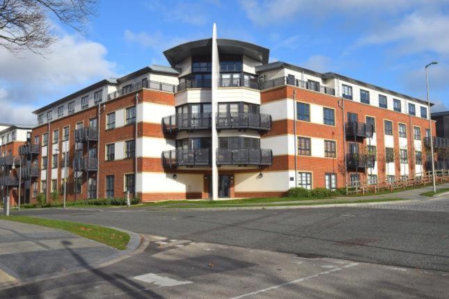 法恩伯勒Blue Sky Apartments @Wallis Square, Farnborough的街道上一座大型砖砌建筑,设有阳台