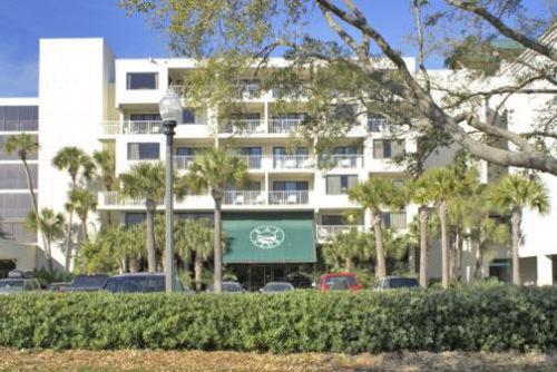 德斯坦Bay Club of Sandestin, a VRI resort的一座白色的大建筑,前面有棕榈树