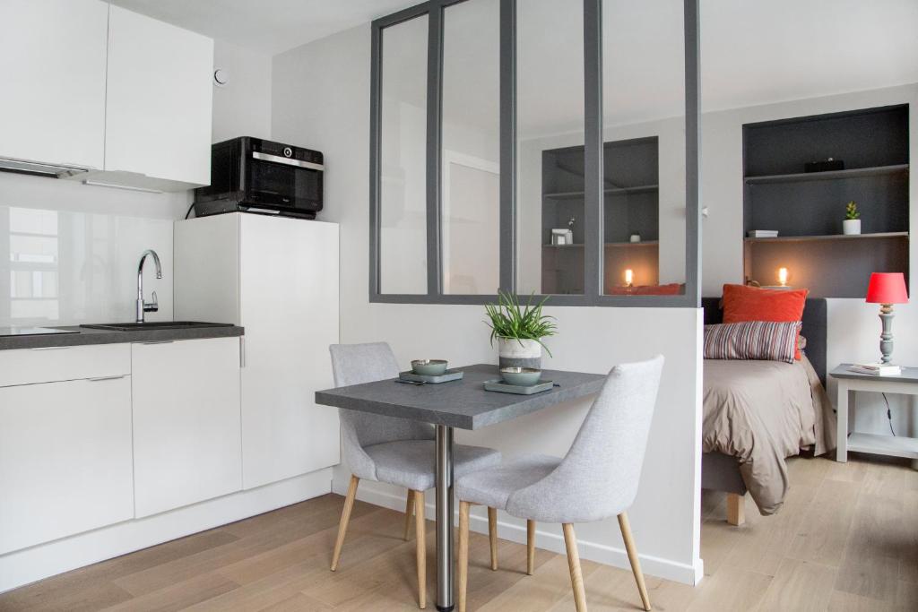 里尔Stay Appart Hotel Lille Centre的厨房以及带桌椅的起居室。