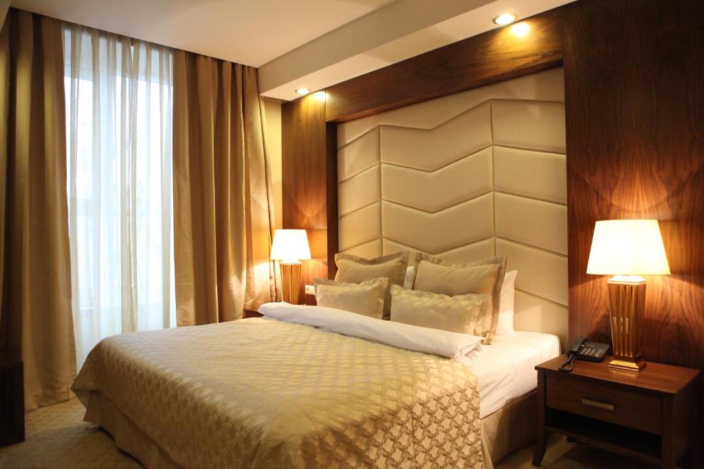 切博克萨雷伏尔加高级酒店的一间卧室配有一张床、两盏灯和一个窗户。