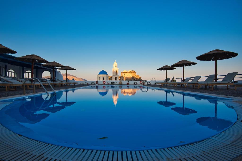 阿克罗蒂里锡拉岛海豚酒店的黄昏时带椅子和遮阳伞的游泳池