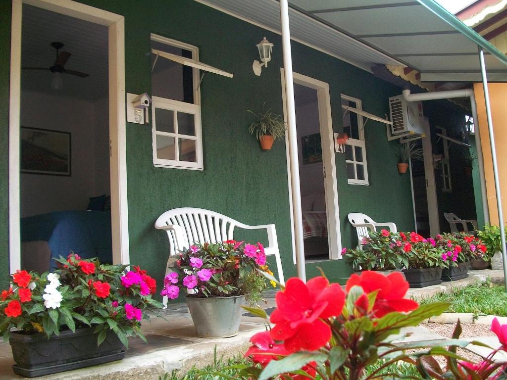 格拉玛多Hospedagem Da Laranjeira Gramado的门廊上鲜花盛开的绿色房子