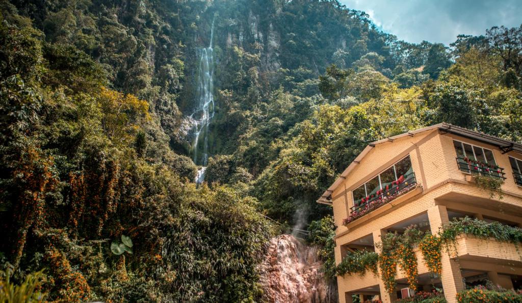 圣罗莎德卡瓦尔Termales Santa Rosa De Cabal的山前一座建筑物后面的瀑布