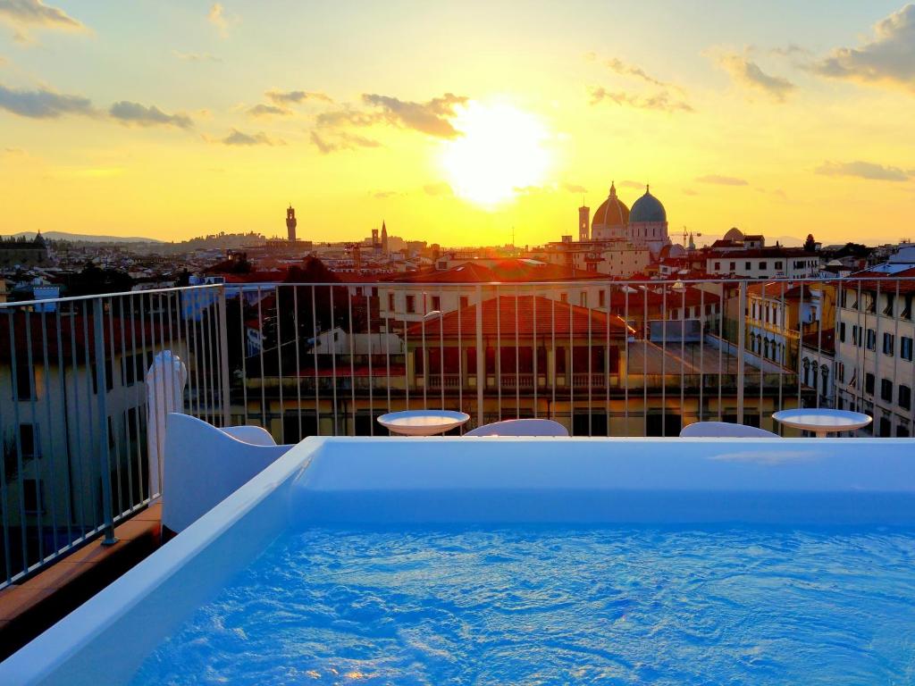 佛罗伦萨十六号城堡景观SPA公寓式酒店的一座享有日落美景的建筑屋顶上的热水浴池
