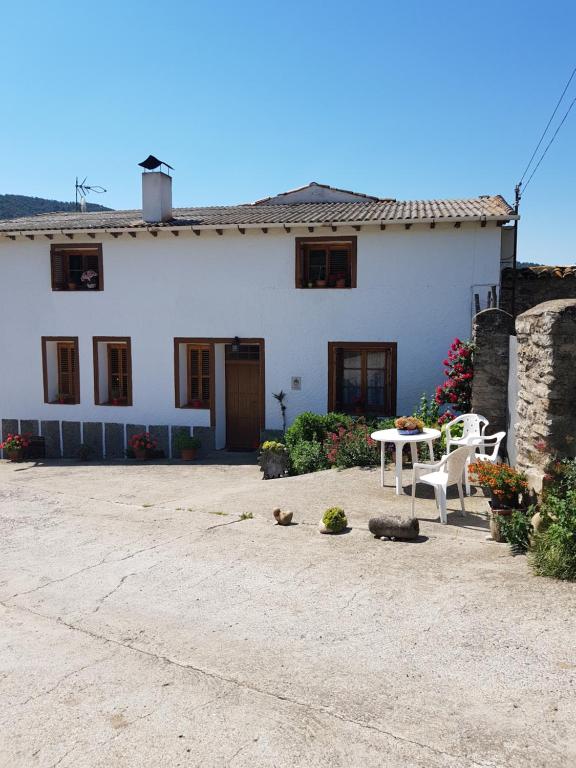 伊萨韦纳河畔罗达Casa "La Huerta" DE RODA DE ISABENA的白色的房子,配有两把椅子和一张桌子
