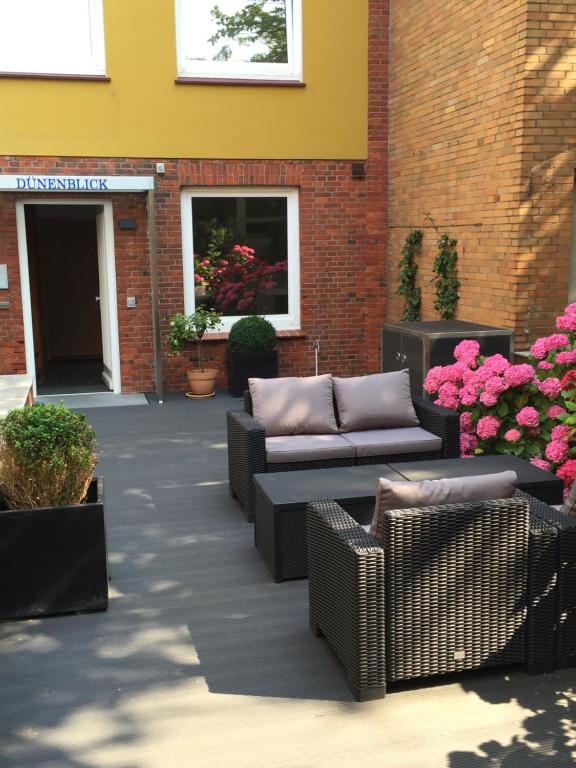 黑尔戈兰岛Dünenblick Apartments的一座建筑前方的庭院,庭院里长着长沙发和鲜花