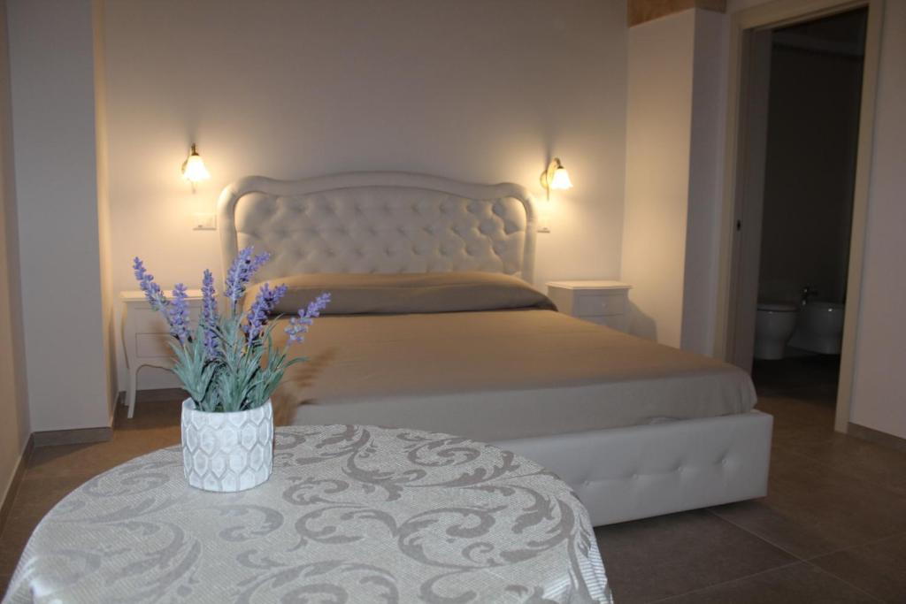 奥里亚B&B Ilenia的一间卧室配有一张床和一张紫色花卉桌子