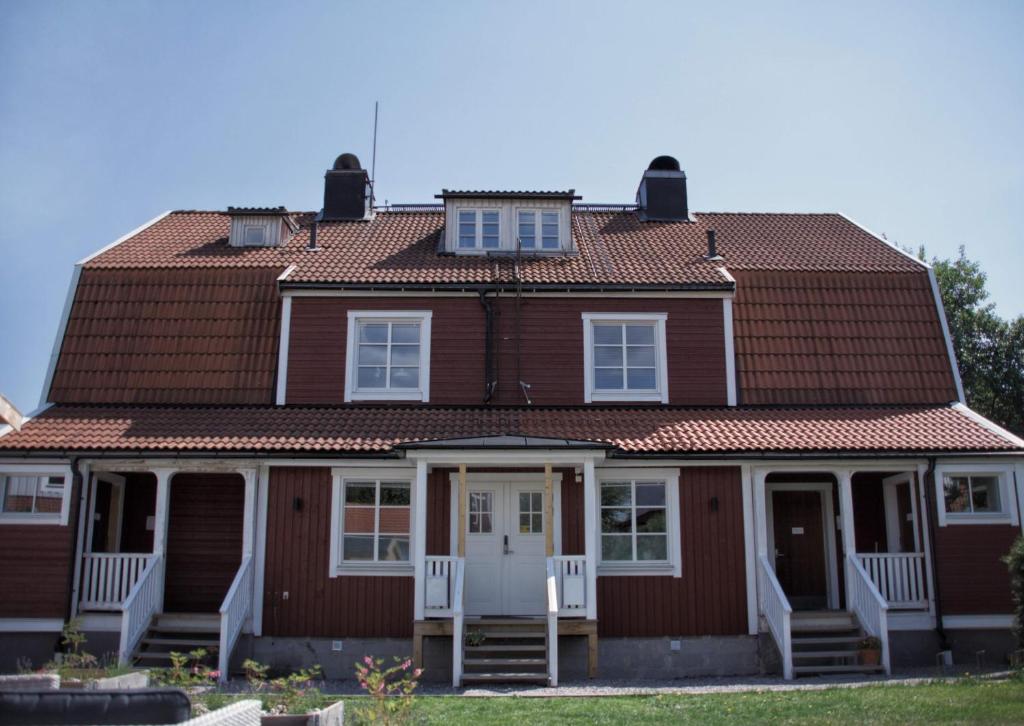 耶夫勒Gavle Apartments Hotel - Lexegränd的棕色的房子,设有瓷砖屋顶和白色椅子