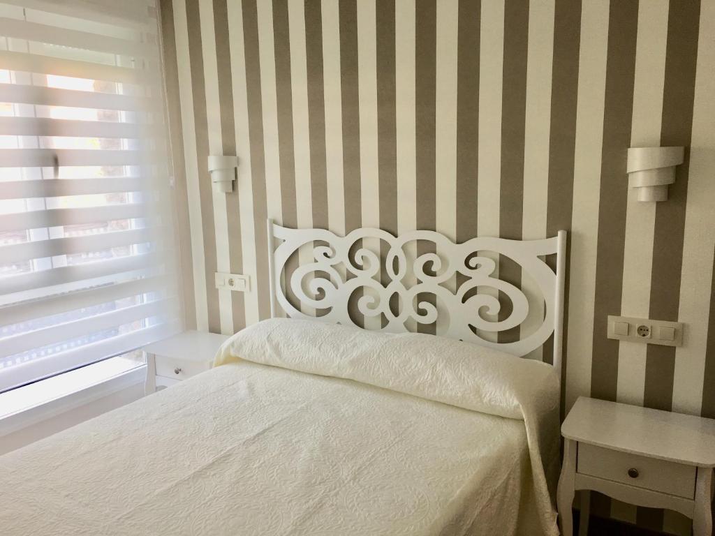 哈兰迪雅·德·拉·维尔APARTAMENTO SAN MIGUEL N.2的卧室配有白色的床和条纹墙