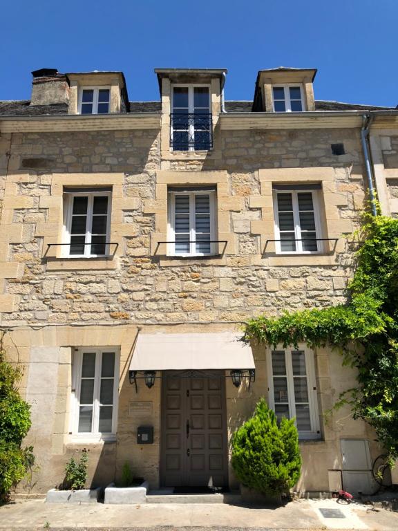 特拉松Les Maisons du Périgord的一座带窗户和门的古老石头建筑