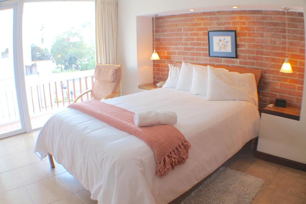 危地马拉雷佛马公寓式酒店的一间卧室设有一张带砖墙的大床