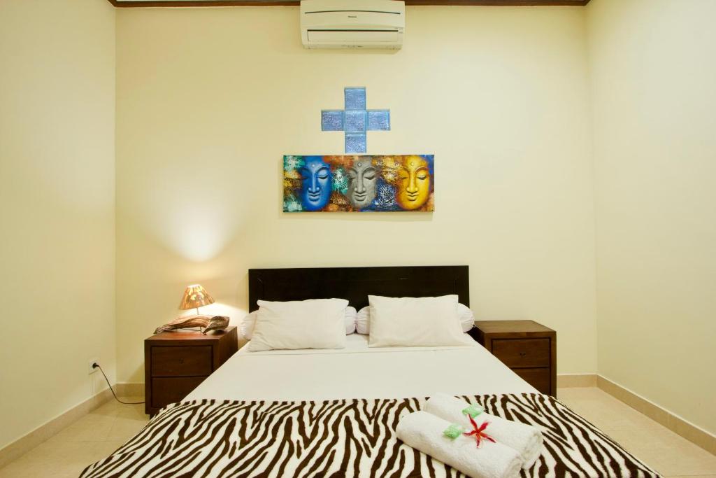 沙努尔巴厘岛沙努尔杰普住宿加早餐旅馆的卧室配有一张床,墙上有十字架