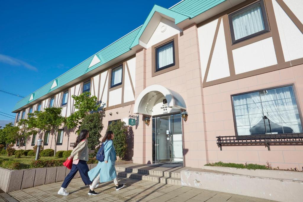 Takahata高畠民宿乐园酒店的两名妇女走在大楼前