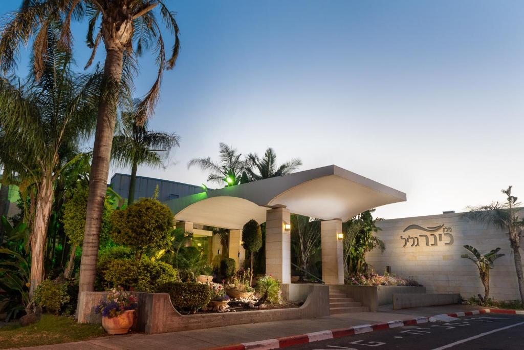 Kinar加利利基纳尔酒店的前面有棕榈树的建筑