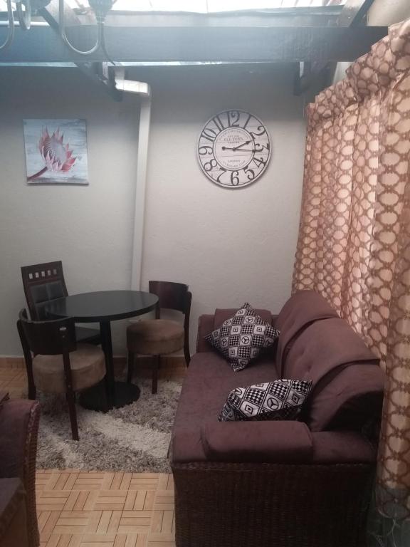 利隆圭Avon Apartments的客厅配有沙发和墙上的时钟