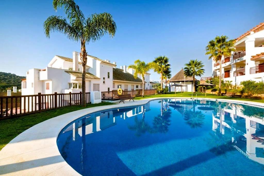 阿尔加德萨Alcaidesa Golf的棕榈树屋前的游泳池
