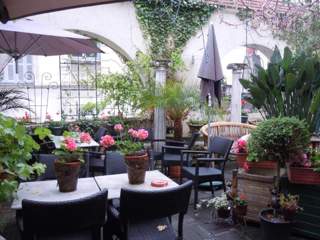 蒙特里夏尔白十字酒店的庭院设有桌椅,种有鲜花和植物
