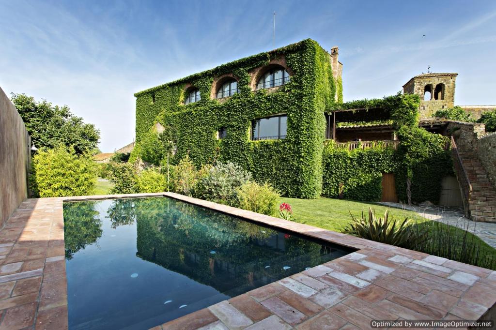 CasavellsEncís d'Empordà -Adults Only-的常春藤覆盖的建筑,房子前设有游泳池