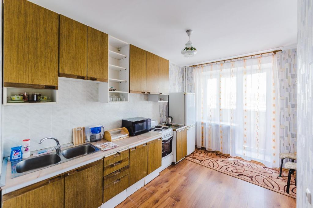 赤塔Dekabrist Apartment Oktyabrski的厨房配有木制橱柜、水槽和冰箱。