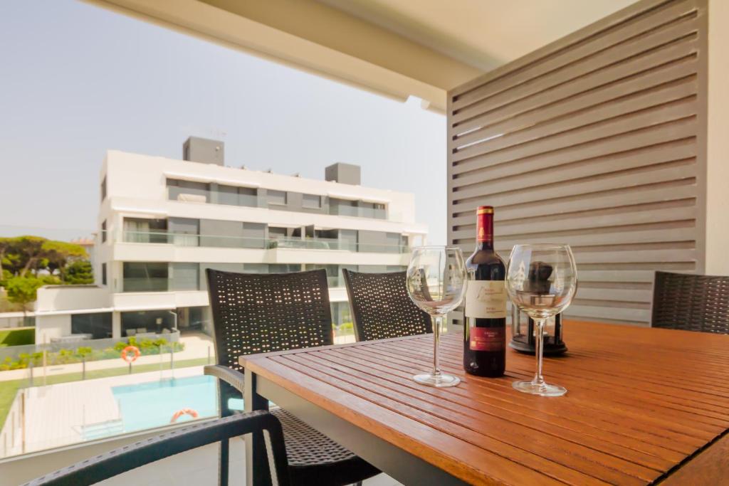 圣玛丽亚港Apartamentos Bahía Blanca的木桌旁的一瓶葡萄酒和两杯酒