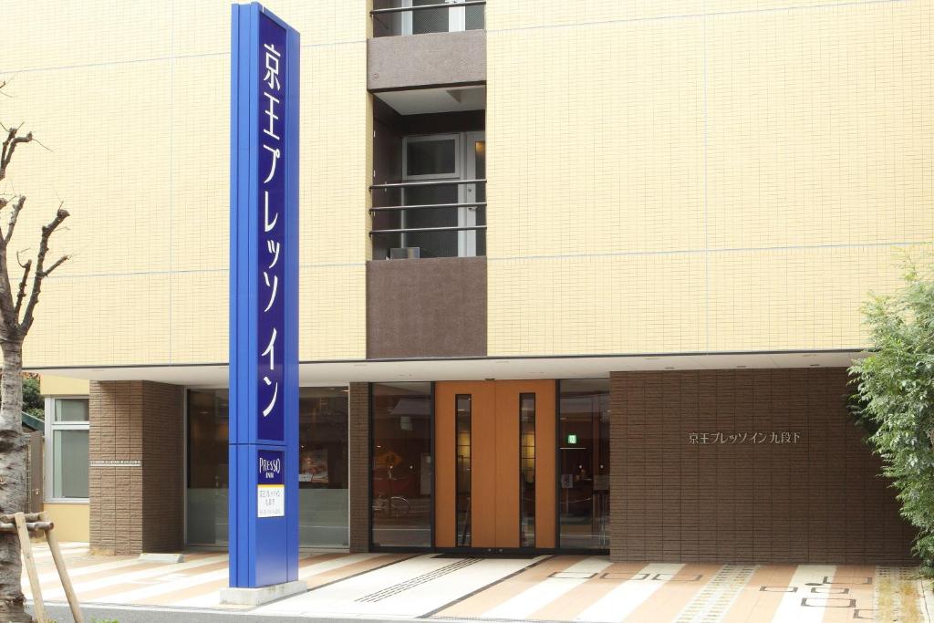 东京Keio Presso Inn Tokyo Kudanshita的前面有蓝色标志的建筑