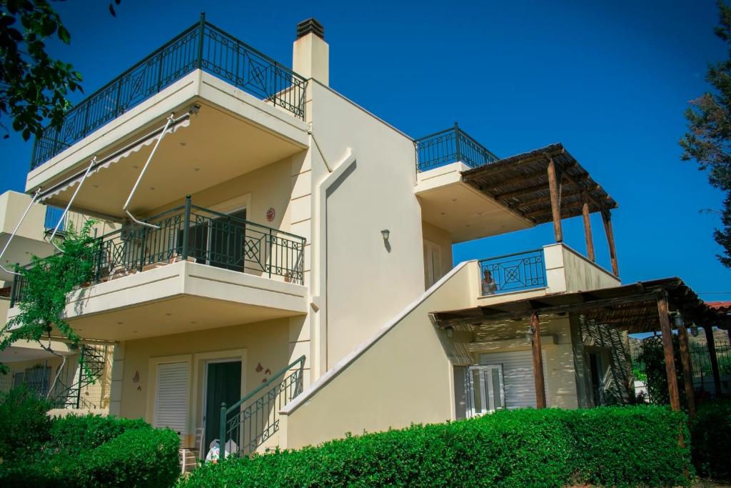 帕莱弗齐亚Anavyssos Cottage的公寓大楼设有阳台和灌木丛