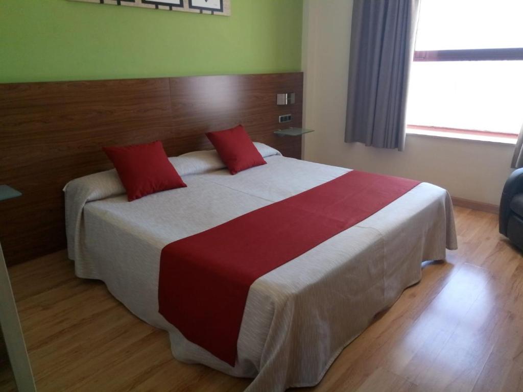 托塔纳奥林匹亚酒店的一间卧室配有一张带红色枕头的大床