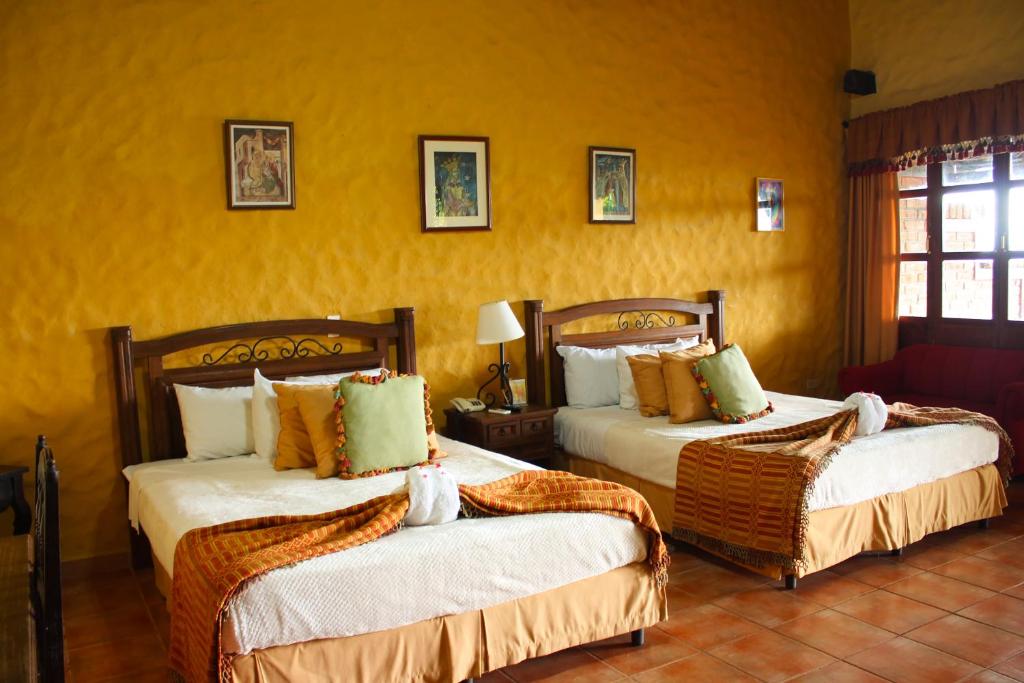 SuchitotoLa Posada de Suchitlan的黄色墙壁客房的两张床