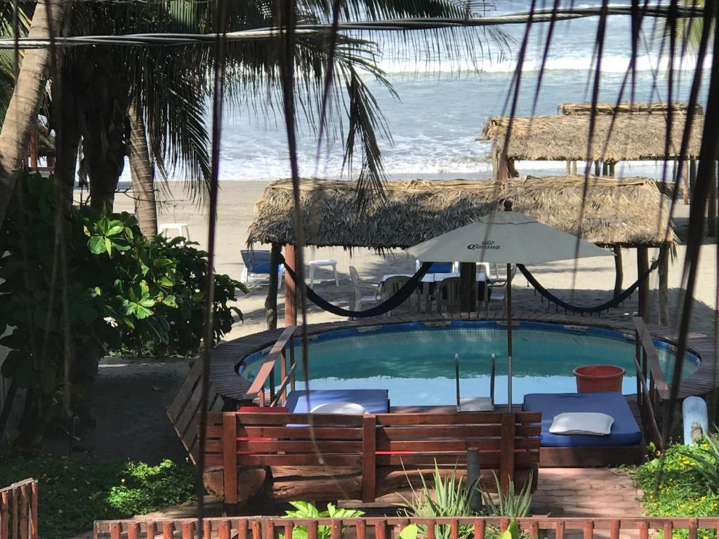 阿卡普尔科Casa de las Olas Surf & Beach Club的一个带遮阳伞的游泳池和一个海滩